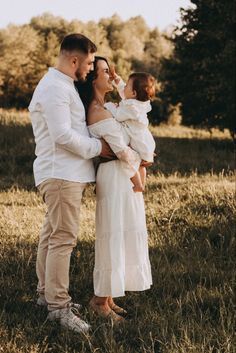 a man and woman holding a baby in a field