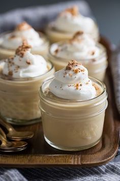 small desserts with whipped cream and cinnamon sprinkles on a wooden tray