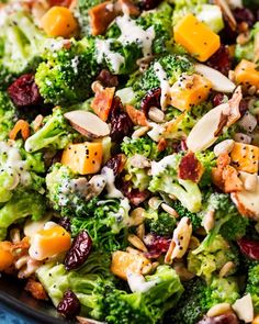 broccoli salad with cranberries and almonds in a black bowl on a blue surface