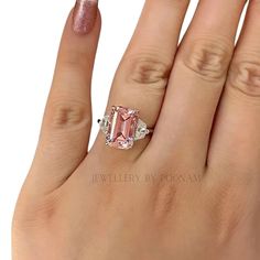 a woman's hand with a pink diamond ring on it