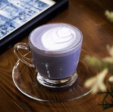 a cup of coffee sitting on top of a glass saucer next to a tablet