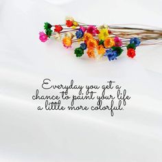 a bunch of colorful flowers sitting on top of a white table next to a quote