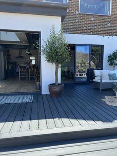 an outdoor deck with chairs and a potted tree