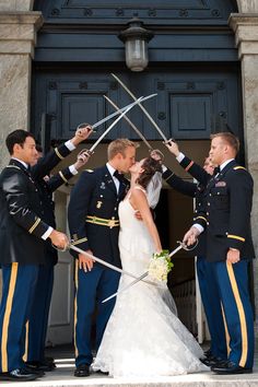 a bride and groom are holding swords in front of the door to their wedding ceremony