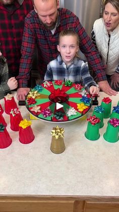 a group of people standing around a table with christmas decorations on it and presents in front of them