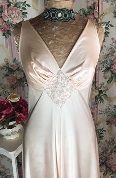 This Olga nightgown is a Powdered Apricot color in size 38(L-XL) in style #9697.  With its captivating charm this nightgown will leave anyone looking like a 1930's glamor movie star!  This is one of Olga's more simple styles, but still it has more than just clean lines, as it has a romantic appeal with just a touch of lace giving it a very chic Hollywood look.  This nightgown is not very stretchy at the bust like most Olga's so the best fit would be for anyone who wears a (L-XL). The skirt is ve V-neck Coquette Sleep Dress, Coquette Satin V-neck Sleepwear, Vintage V-neck Wedding Sleepwear, Feminine Satin Nightgown For Bedtime, Feminine Satin Nightgown For Sleep, Feminine Bias Cut Nightgown For Wedding Night, Vintage V-neck Sleep Dress, Satin Coquette Nightgown For Sleep, Fitted Coquette Nightgown For Wedding Night