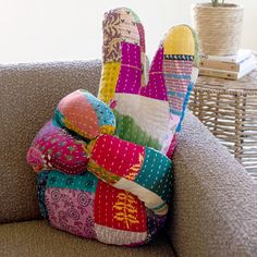 colorful pillows stacked on top of each other on a couch next to a wicker basket