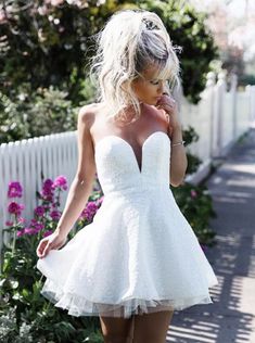 a woman in a short white dress walking down the street