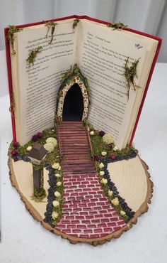 an open book that is sitting on top of a table with flowers and plants in it