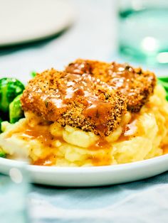 a white plate topped with mashed potatoes covered in gravy and broccoli