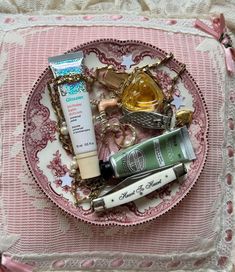 an assortment of beauty products on a pink and white lace doily, with pearls