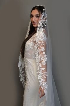 a woman in a wedding dress wearing a veil and holding her hand on her hip