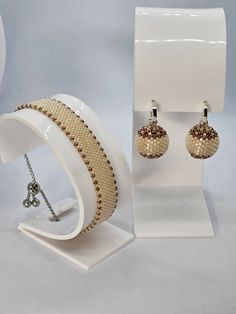 a pair of beaded bracelets and earring set in white display case with stand