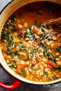 a red pot filled with beans, spinach and parmesan cheese on top