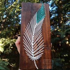 a hand holding up a piece of wood with a white and green leaf on it