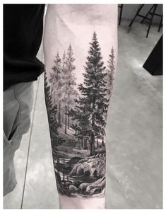 a man's arm with a forest scene on it