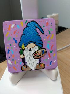 a painting of a gnome with a blue hat on it's head and holding a plate