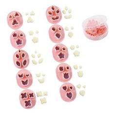 several pink plastic buttons with hearts and faces on them next to a container of white candies