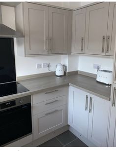 a kitchen with white cabinets and gray counter tops is pictured in this image, there are toasters on the counters