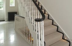 a white staircase with black handrails and lights on the bottom step, in a house