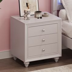 a white night stand with two drawers and a plant on the nightstand next to it