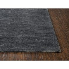 a dark gray rug on top of a wooden floor