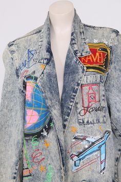 vintage hand painted denim jacket indigo color denim with acid wash hand painted travel + city design iridescent sequin accents San Francisco, London NYC Twin Towers skyline open blazer front mid length fold over collar circa 1980s/90s oversized fit Tagged, Medium-fits like OSFM 46 inch bust 31 inch length 24 inch sleeve 17 inch shoulder good vintage condition, nothing serious to note. design is hand painted with neon puffy paint, air brush, hand brush work, one of a kind please note that it has Trendy Spring Outerwear With Graffiti Print, Multicolor Denim Summer Outerwear, Trendy Graffiti Print Denim Jacket For Spring, Multicolor Denim Outerwear With Graphic Print, Multicolor Denim Jacket With Graphic Print, Trendy Medium Wash Outerwear For Festival, Vintage Graphic Print Denim Jacket For Spring, Vintage Denim Jacket With Graphic Print For Spring, Fitted Graffiti Print Outerwear For Spring