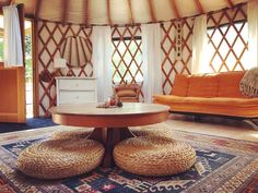 the inside of a yurt with two couches and a table in front of it