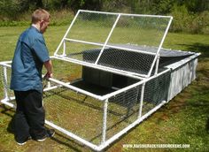 a man standing next to a chicken coop in the middle of a grass covered field