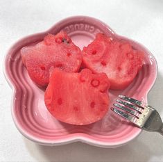 two pieces of watermelon are on a pink plate with a fork in it