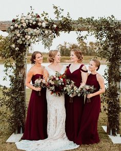 the bride and her bridesmaids are standing under an arch decorated with greenery