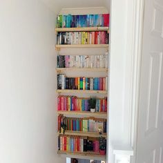 a bookshelf filled with lots of books next to a white door in a room