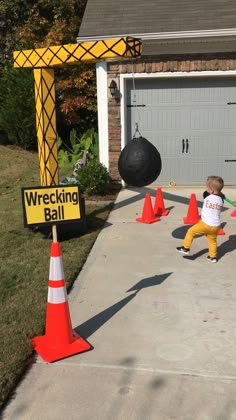 a young boy is kicking around cones in front of a building with a wrecking ball on it