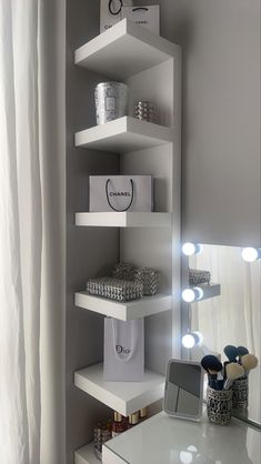 a white shelf filled with lots of boxes and lights in front of a mirror on the wall