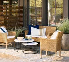 wicker furniture on patio with plants and potted grass in front of large windows