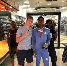 two young men standing next to each other in front of a store with people taking pictures