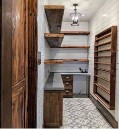 an empty pantry with wooden shelves and shelvings on the wall, next to a tiled floor