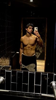 a shirtless man taking a selfie in front of a mirror with his cell phone