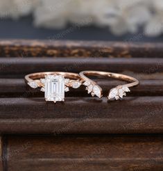 two rings with leaves on them sitting on top of a wooden table next to flowers