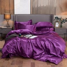 a bed with purple sheets and pillows in a room