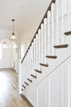 a white staircase with wooden handrails and wood flooring in a home's entryway