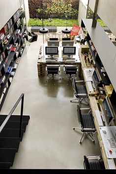 an office filled with lots of desks and chairs next to a book shelf full of books