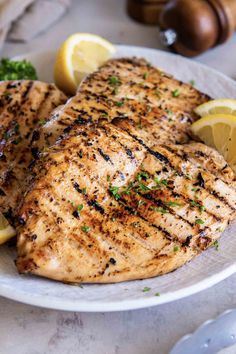 grilled chicken with lemons and broccoli on a white plate