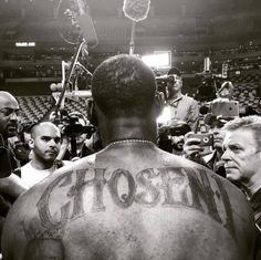 the back of a man's head with tattoos on it and people around him