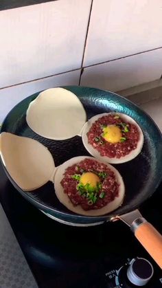 three eggs are being cooked in a frying pan on the stove with other ingredients