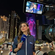 a woman is holding a microphone in front of a television screen with a man on it