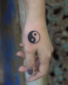 a woman's hand with a small tattoo on her left wrist and the symbol for yin