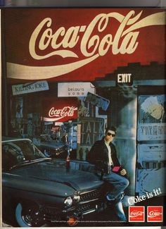 a man sitting on top of a car in front of a coca cola advert