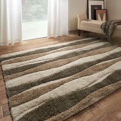 a living room with a large rug on the floor next to a chair and window