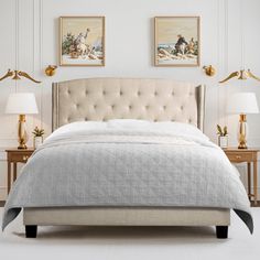 a bedroom with white walls and two lamps on either side of the bed, along with an upholstered headboard